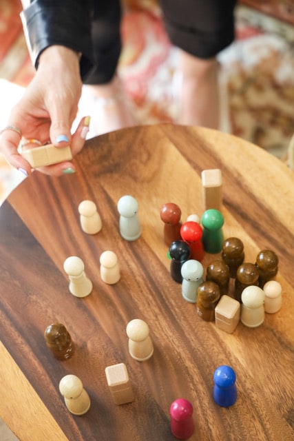 Anja Ogris ordnet Figuren für die systemische Arbeit auf einem Holztisch